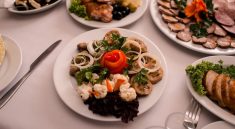 Beautifully arranged gourmet plates with meats, cheeses, and garnishes on a white table setting.