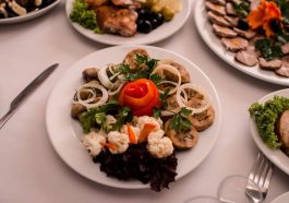 Beautifully arranged gourmet plates with meats, cheeses, and garnishes on a white table setting.